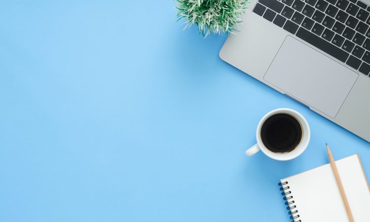 laptop and coffee mug from above on blue background