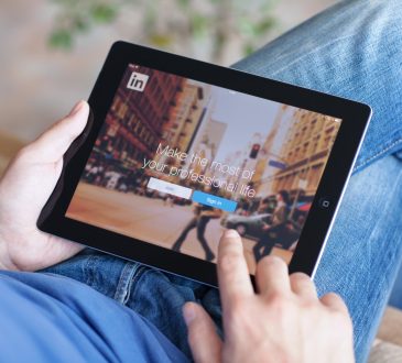 Man holding iPad with App LinkedIn on the screen