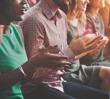 people sitting in chairs clapping at conference