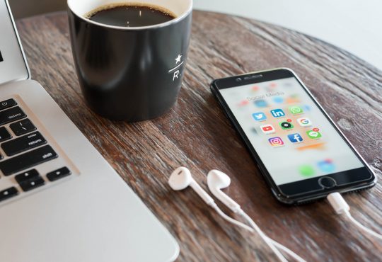 Phone on table beside laptop and coffee mug
