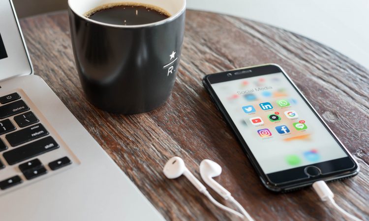 Phone on table beside laptop and coffee mug