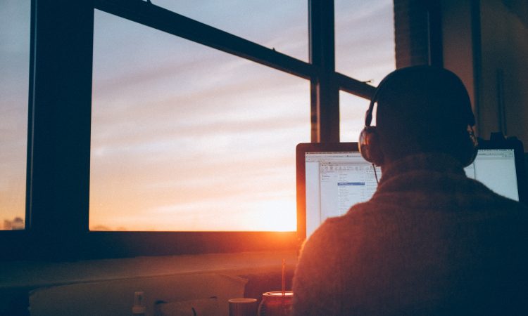 man sitting at desk in front of computer screen with headphones on