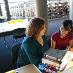 female mentor and mentee sitting together in library
