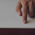 close up of hand of person reading braille