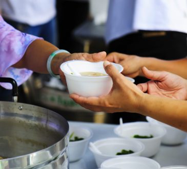woman handing bowl of soup out in kitchen