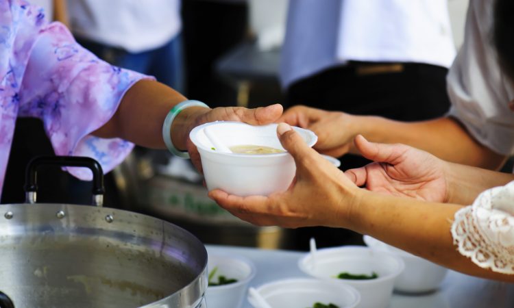 woman handing bowl of soup out in kitchen