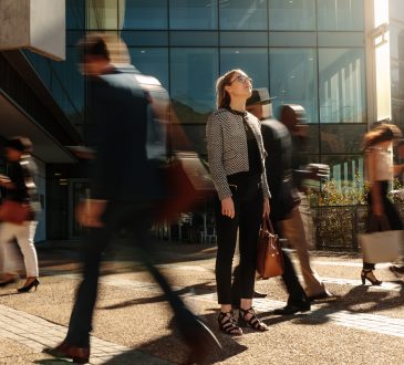 Woman standing amidst a busy office-going crowd