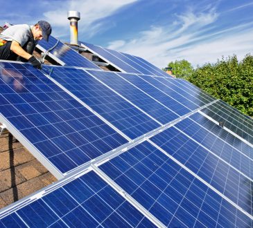 Man installing alternative energy photovoltaic solar panels on roof