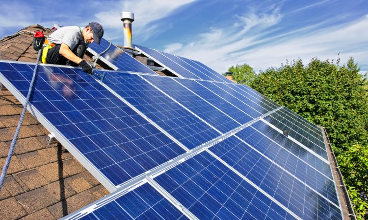 Man installing alternative energy photovoltaic solar panels on roof