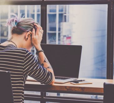 person with head in hands in front of computer
