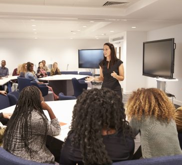 Female teacher addressing university students in a classroom