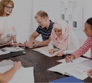 diverse group of people sitting around table listening to instructor