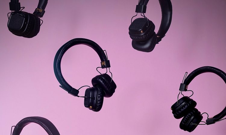 multiple pairs of over ear headphones floating on purple background