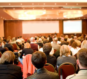 Rear view of many listeners sitting on chairs during lecture at conference
