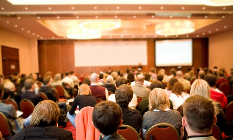 Rear view of many listeners sitting on chairs during lecture at conference