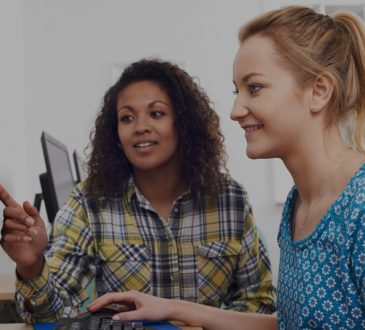two women sitting at computer together