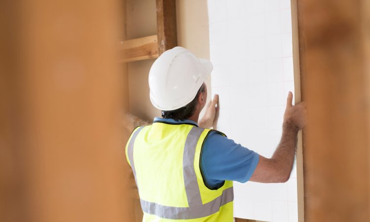 Builder Fitting Insulation Boards Into Roof Of New Home