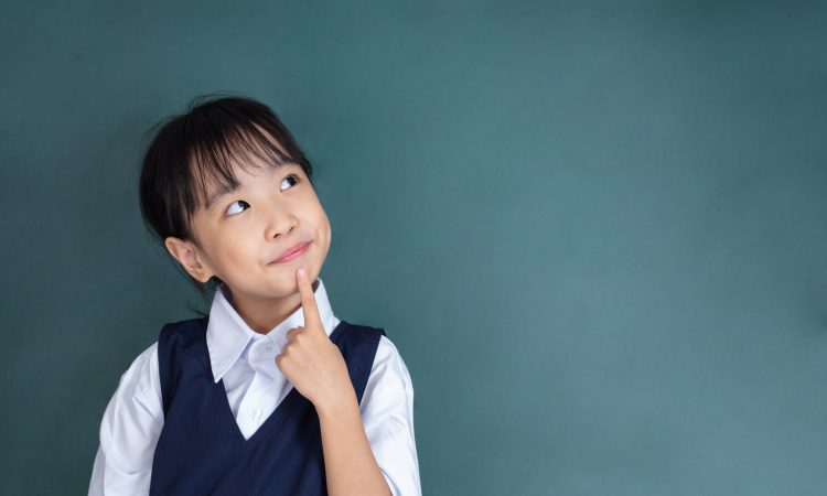 little Girl thinking with finger on chin against green blackboard