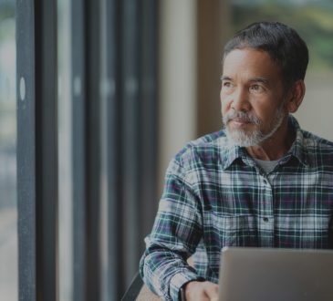 man sitting out computer looking out window