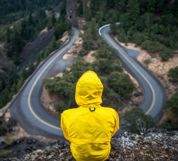 person sitting on hill overlooking winding road