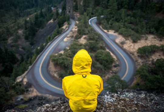 person sitting on hill overlooking winding road