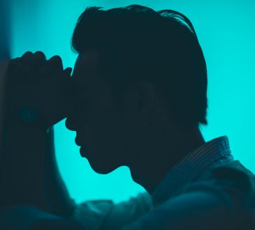 man leaning head on hands against wall