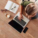 Top view of woman using laptop sitting at table