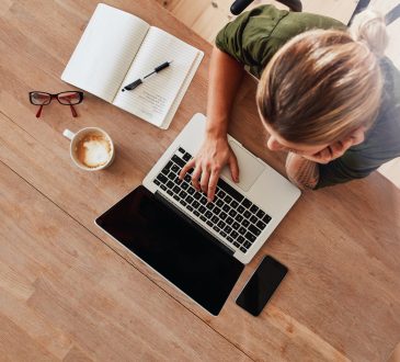 Top view of woman using laptop sitting at table