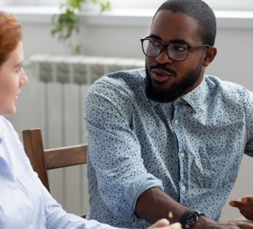 man and woman sitting and talking in office