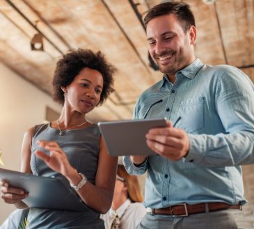 man and woman talking together in office looking at ipads