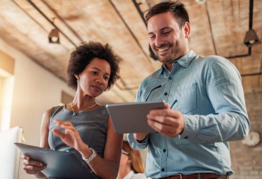 man and woman talking together in office looking at ipads