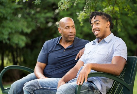 dad talking to son on park bench