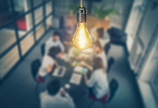 Light bulb hanging over people meeting at table
