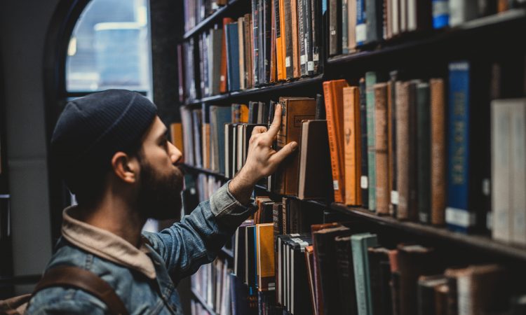 man looking at book in library