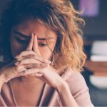 young woman pressing head into hands