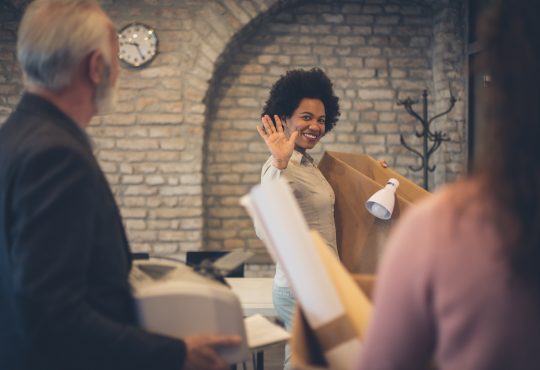 woman waving to colleagues leaving office