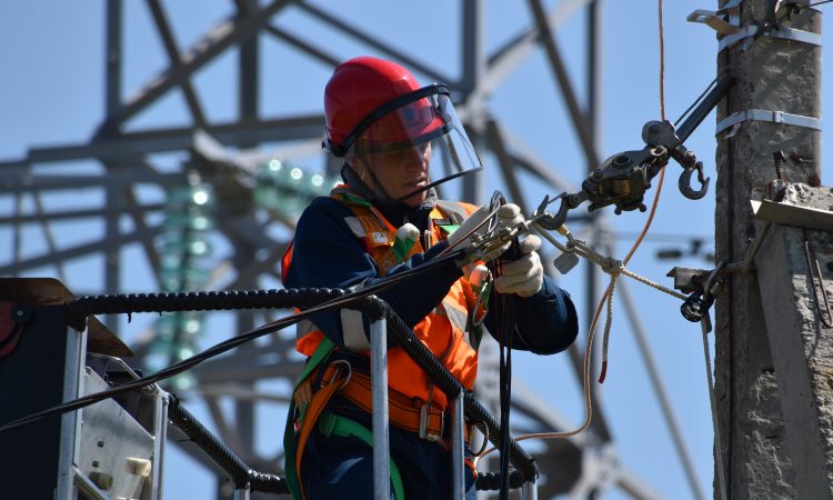 man fixing steel cable attached to pole