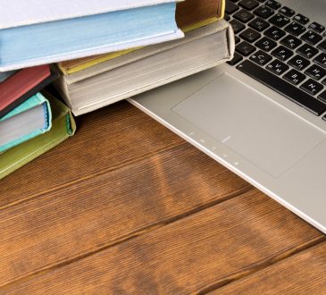 Books and laptop on wooden table.