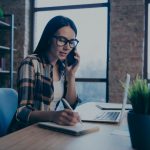 woman on phone taking notes