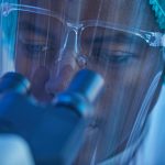 close up of man looking through microscope