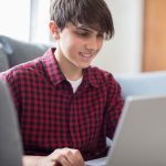 Teenage Boy Working On Laptop At Home