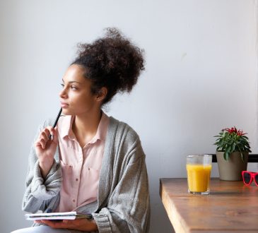 Portrait of a young woman sitting at home with pen and paper