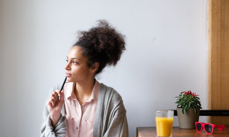 Portrait of a young woman sitting at home with pen and paper