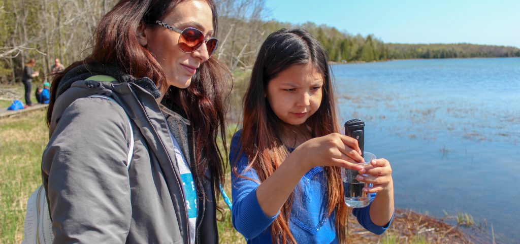 woman and girl looking at water in test tube