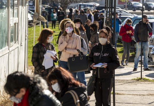 People wearing face masks in an attempt to prevent the spread of coronavirus disease COVID-19 wait in line in front of an office of the labor bureau.