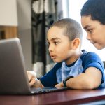 two boys using laptop