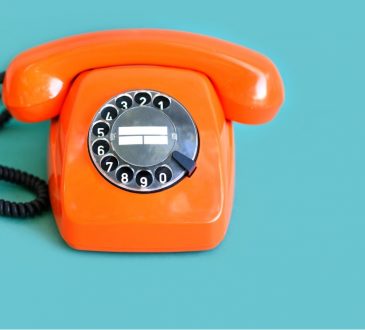 orange rotary phone on blue background