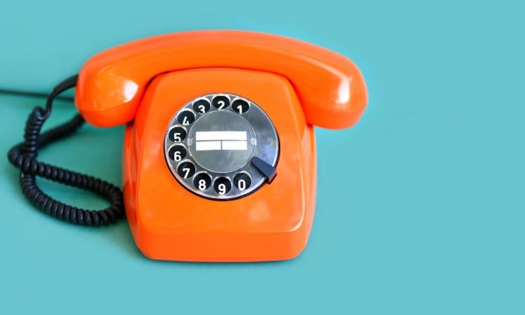 orange rotary phone on blue background