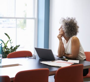 Middle aged woman looking out of the window in the boardroom