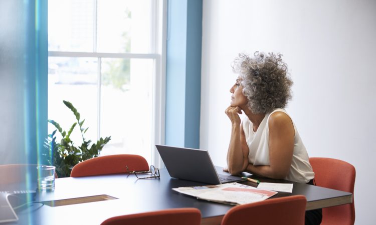 Middle aged woman looking out of the window in the boardroom